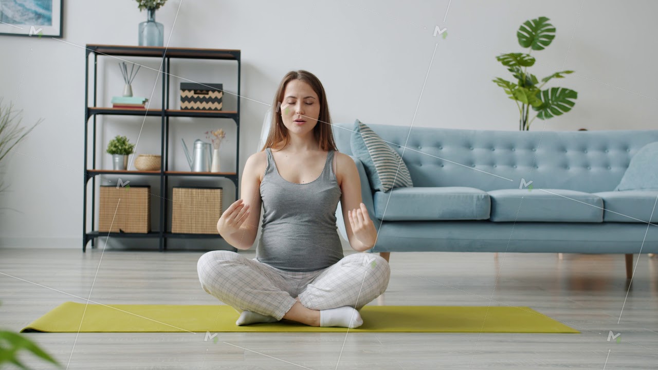 Pregnant girl sitting in lotus position on yoga mat breathing relaxing enjoying peace and